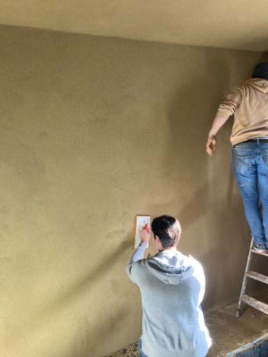Handwerker trägt glatten Lehmputz auf rohe Wand auf – nachhaltig, atmungsaktiv und warm. 