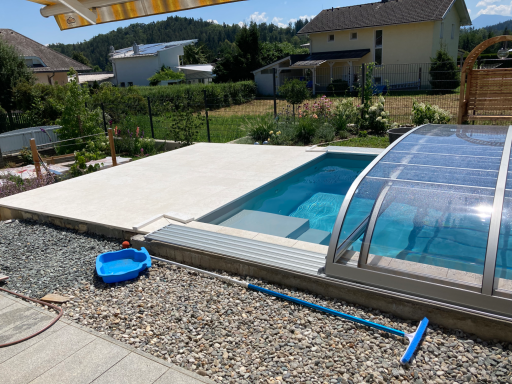 Whirlpool mit Glasfaser-Geländer, Polycarbonat-Verdeck und Steinpflaster inmitten Kies, Pflanzen & Alpenblick.